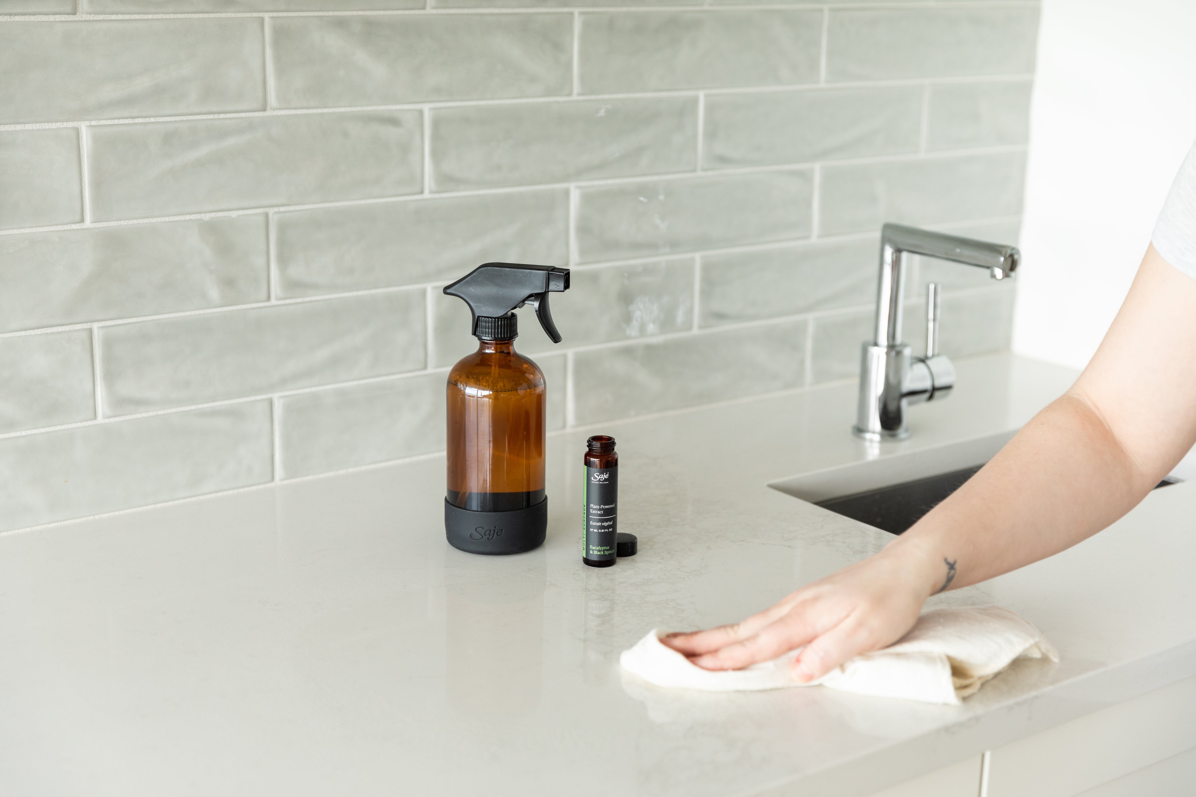 A person using Saje multi-surface cleaner to clean their kitchen